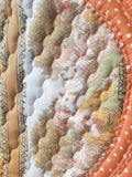 Full view of 40-inch round paneled orange coiled fabric rug on gray floor